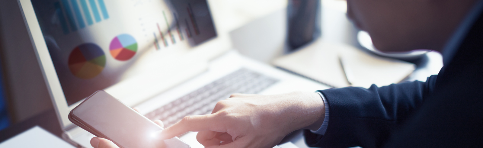 Close up of businessman hand working on smartphone and laptop computer with financial business graph information diagram