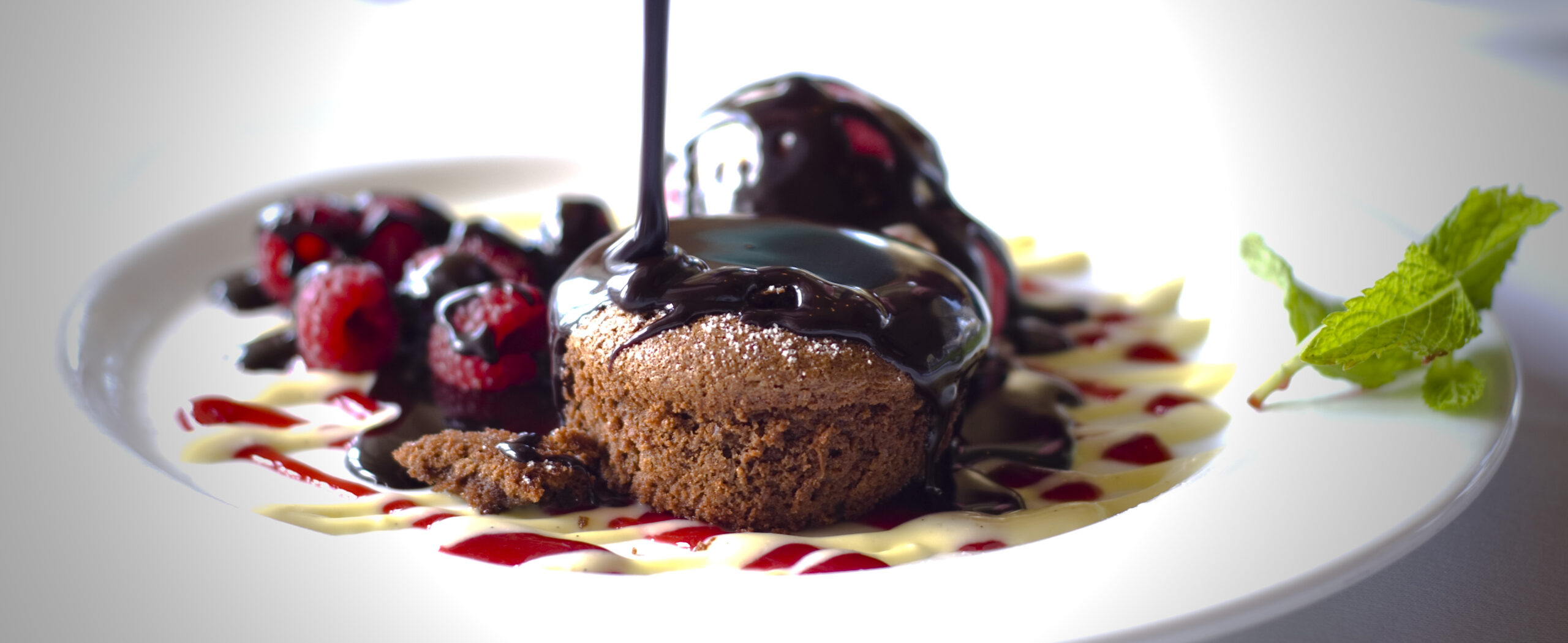Chocolate is poured on a chocolate souffle dessert plate