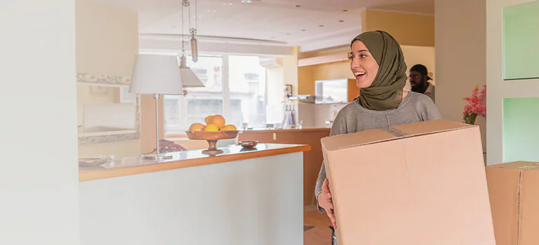 women in hijab carrying a big cardboard box and walking forward