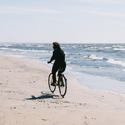 woman riding her bicycle on the beach shore after investing in mutual funds