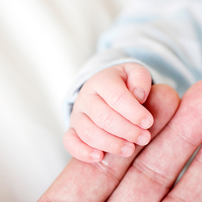 tiny hands of an infant holding onto an elder's hand