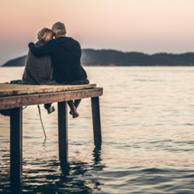 senior man and woman sitting near to lake enjoying their retirement life