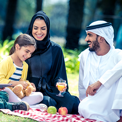 young family of father, mother and daughter having picnic in park