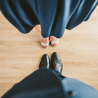 young man and woman looking down at their shoes from top symbolising they're getting married
