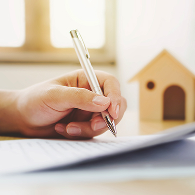 human holding a pen with a background of house emphasising home protection solutions