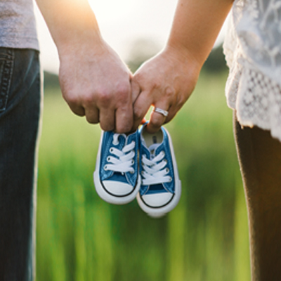 couple holding pair of infant shoes after insuring their family
