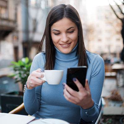 woman enjoying her espresso and looking at her mobile when her personal loan is approved
