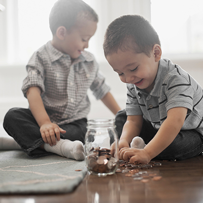 two toddler kids playing with coins by taking them out from the jar