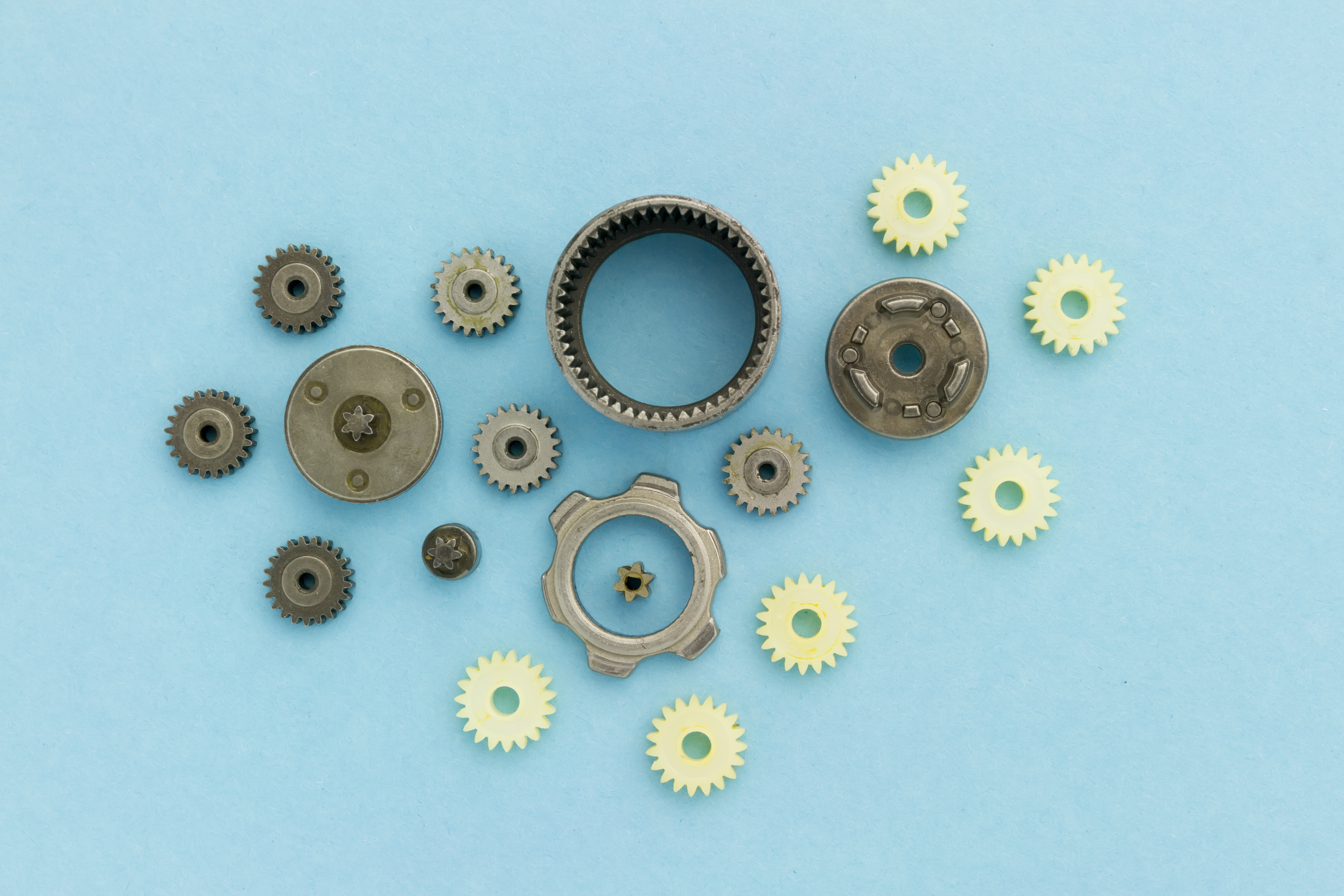Metal and palstic gears of dismantled mechanism laying on blue background
