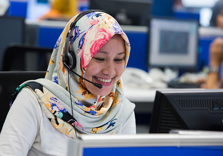 Woman sat at computer using headset