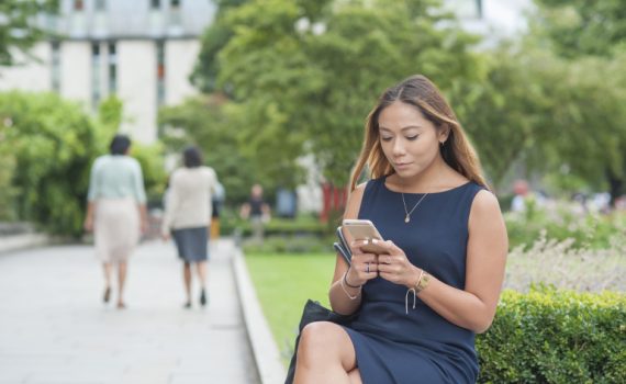 Woman sitting on bench using phone