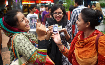 Three females chatting and viewing something on mobile