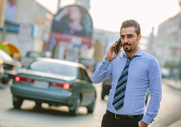 man talking on phone while crossing street