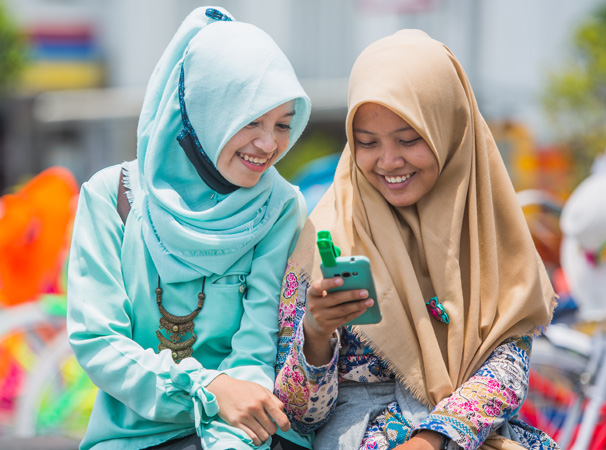 Shariah compliant girls on phone engaging with global network