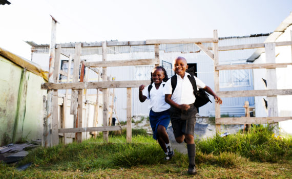 Excited young brother and sister running from their township