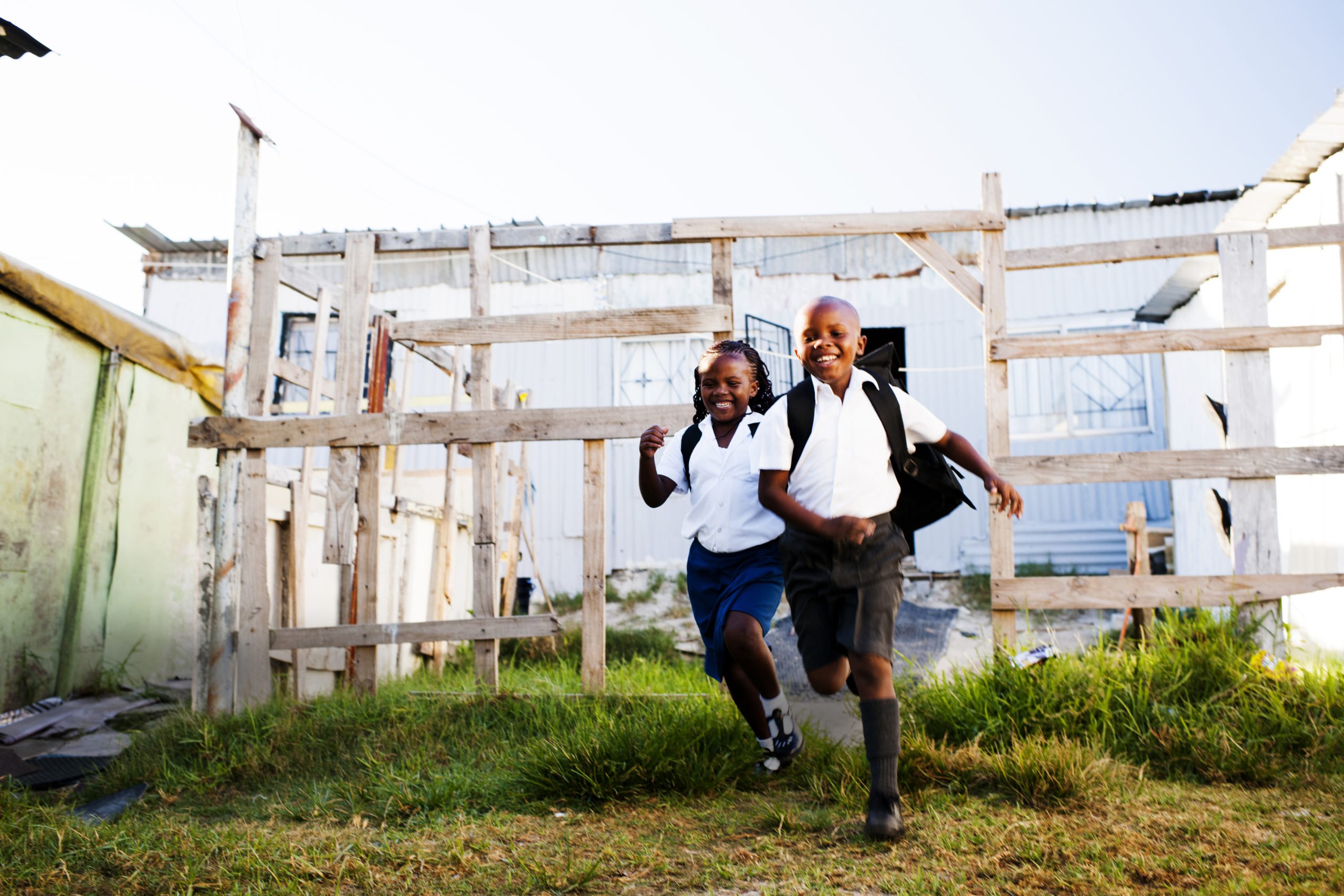Excited young brother and sister running from their township