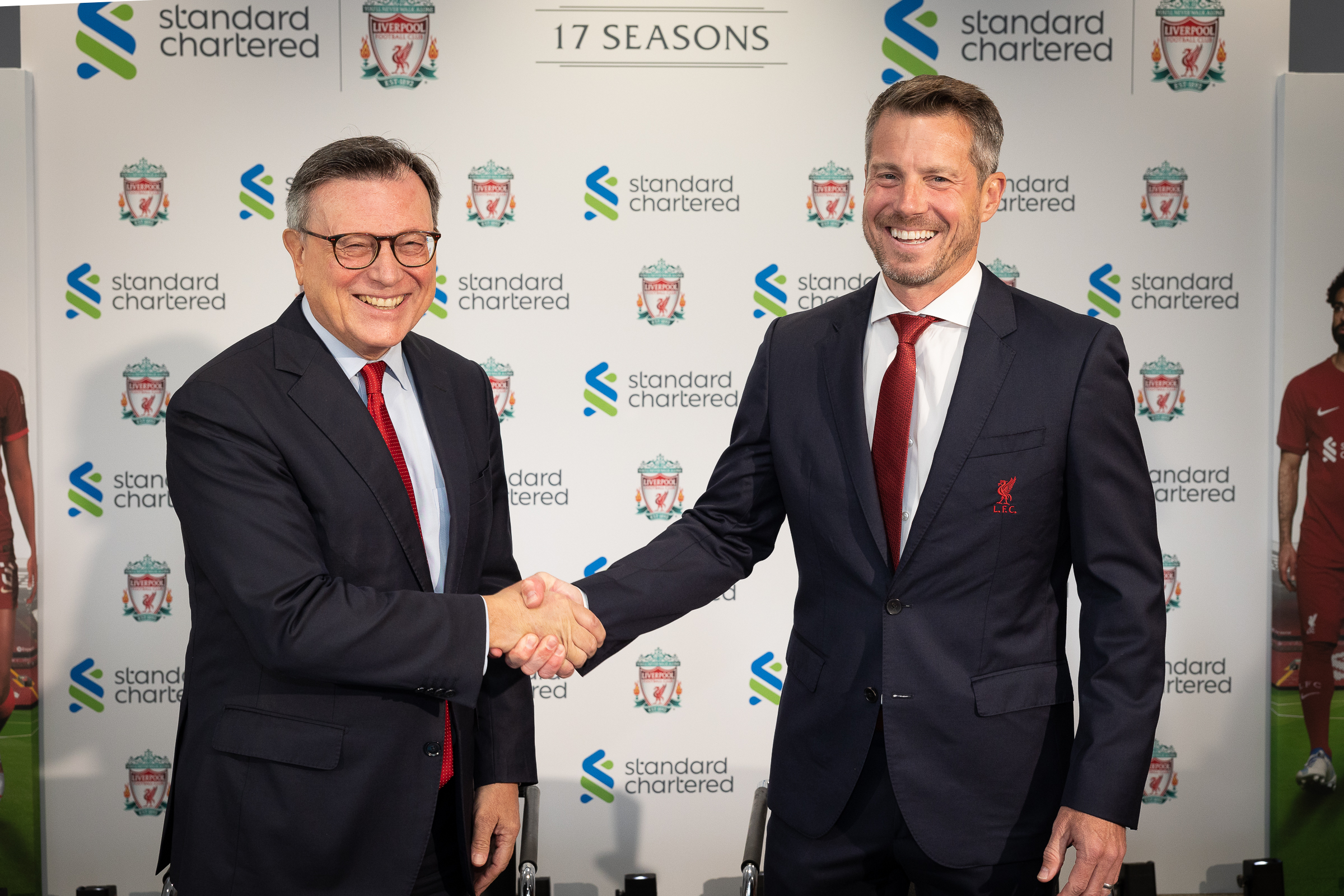 Standard Chartered's Chairman and Liverpool FC's CEO shake hands to mark sponsorship extension