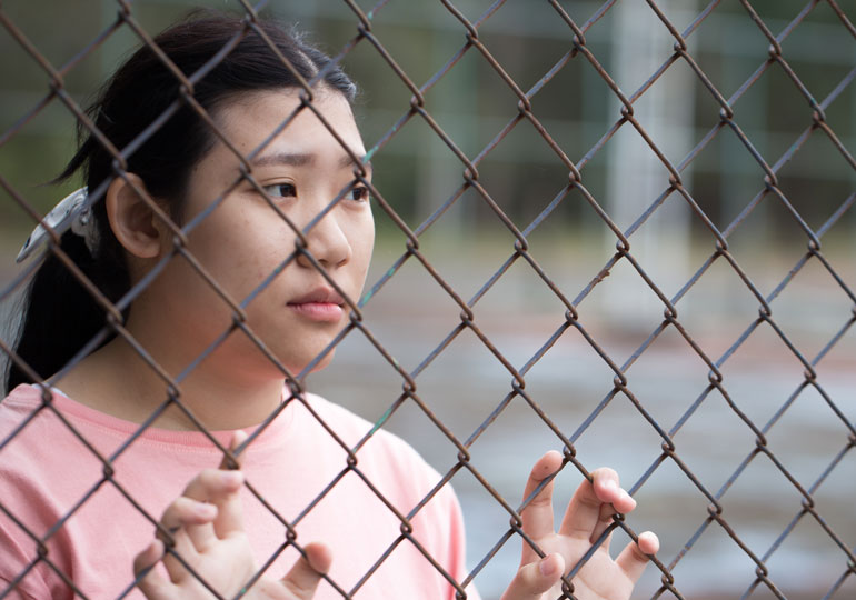 Girl behind wire fencing