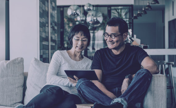 Couple smiling at tablet sitting together