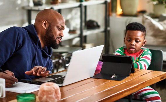 Man and child using laptops on wooden table