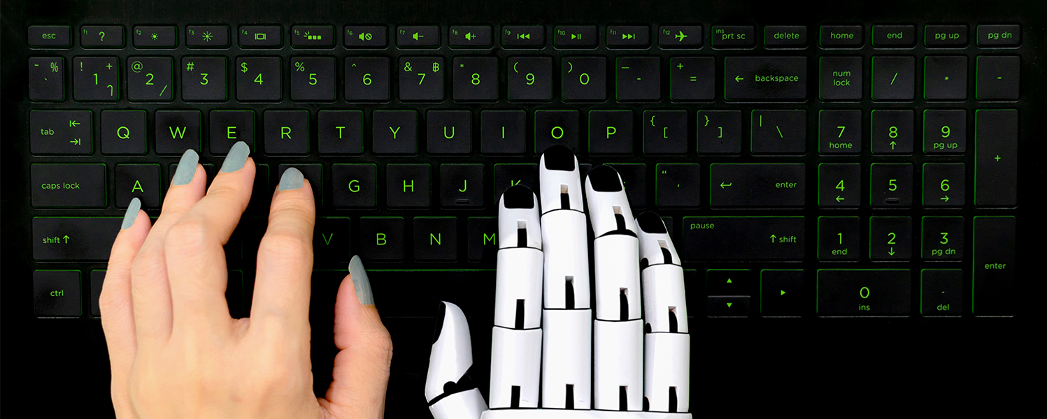 Robot hand and human hand on a computer keyboard depicting AI assisting humans