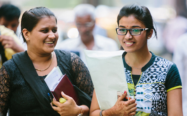 Two women smiling and holding paperwork