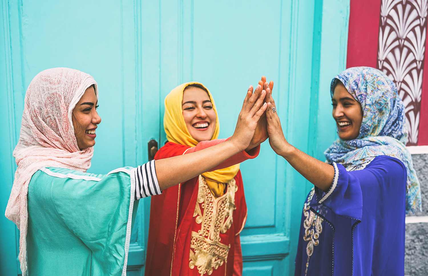 Happy Arabian women stacking hands together outdoor