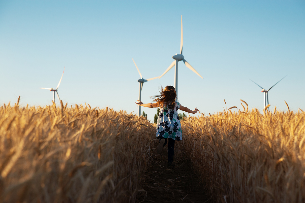 Girl running in a field with turbines