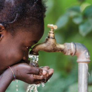 Young girl drinking from an outdoor tap