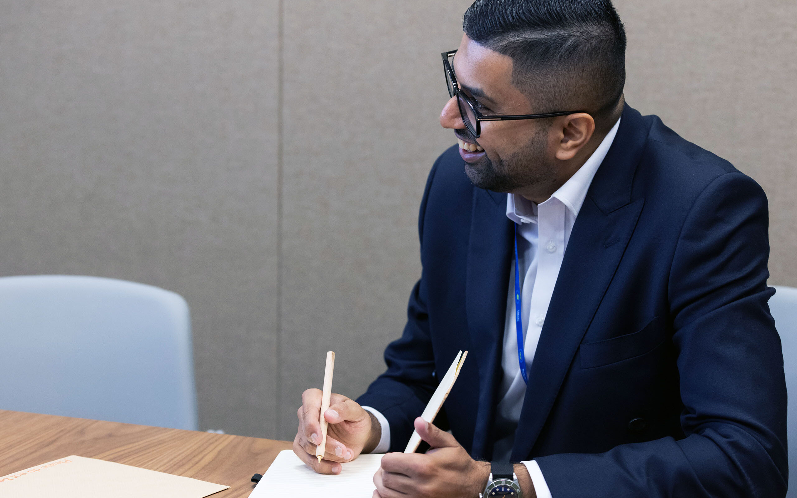 A Standard Chartered colleague smiles while taking notes at work