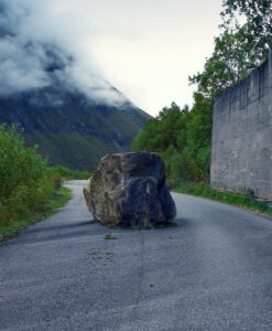 A boulder blocks a road.