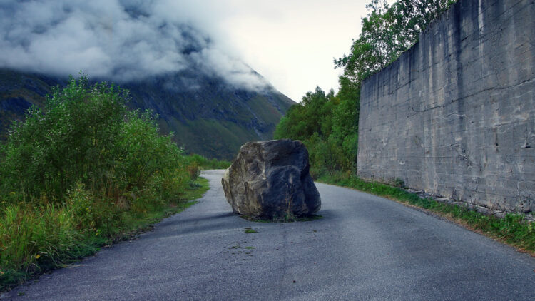 A boulder blocks a road.