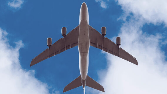 A cargo plane carrying DHL documents flies overhead.