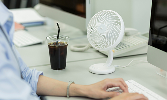 A desk fan next to a computer in an office. We offer tools to make many of our workplaces more comfortable for those experiencing menopause symptoms.