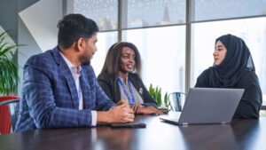 3 people talking with a laptop