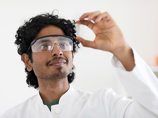 A scientist looks at a vial.