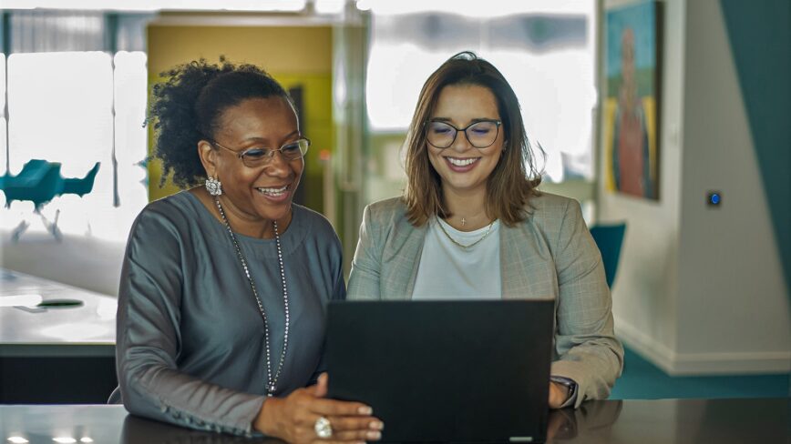 Two women smiling and engaging with a laptop