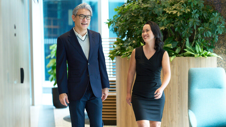 Two experienced career professionals walk down the hallway in a Standard Chartered office.