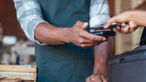 Someone uses contactless payment to pay in a cafe.