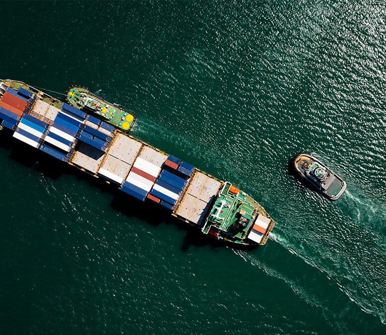 A container ship sails across a green sea.