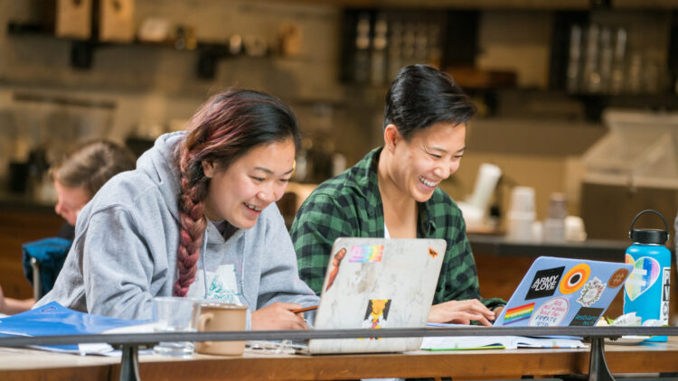 Two women working on laptops in a coffee shop
