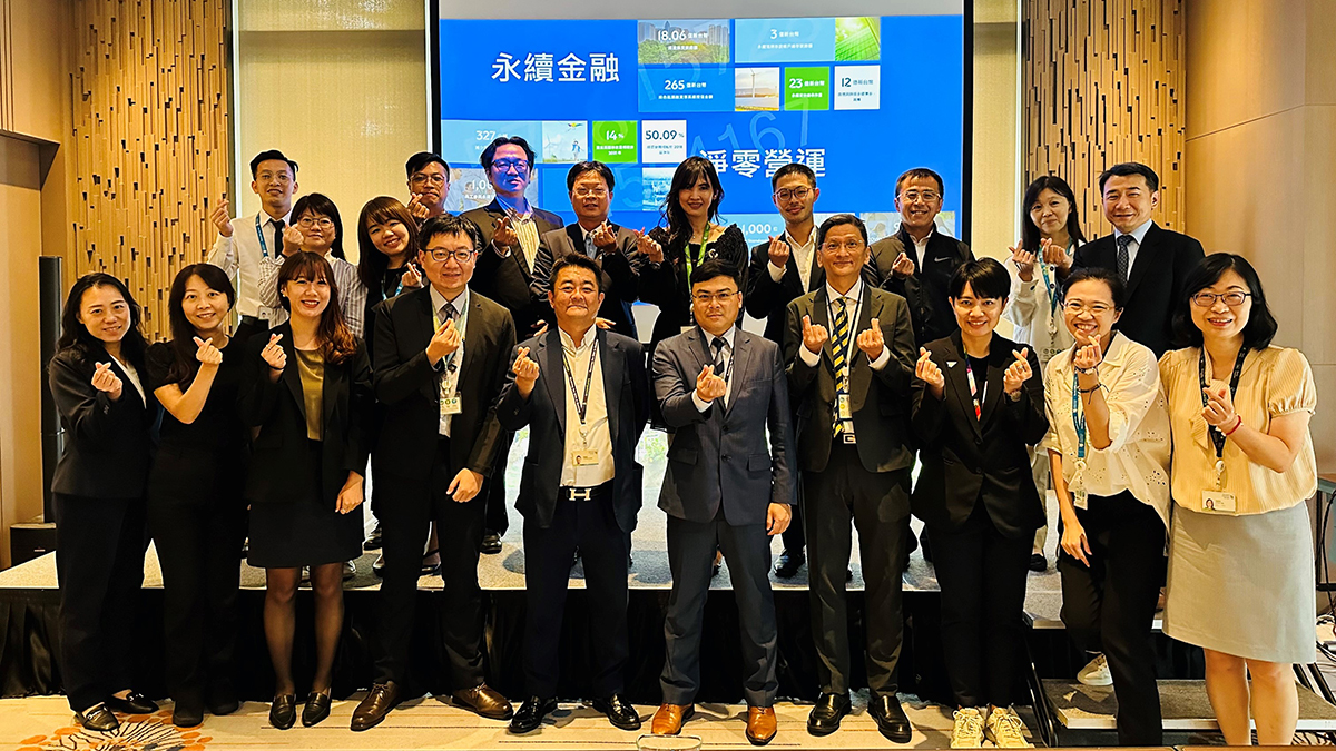 A diverse group of standard chartered colleagues smiling and posing together in front of a large screen