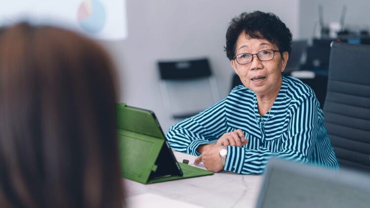 A senior businesswoman runs a meeting using her iPad.
