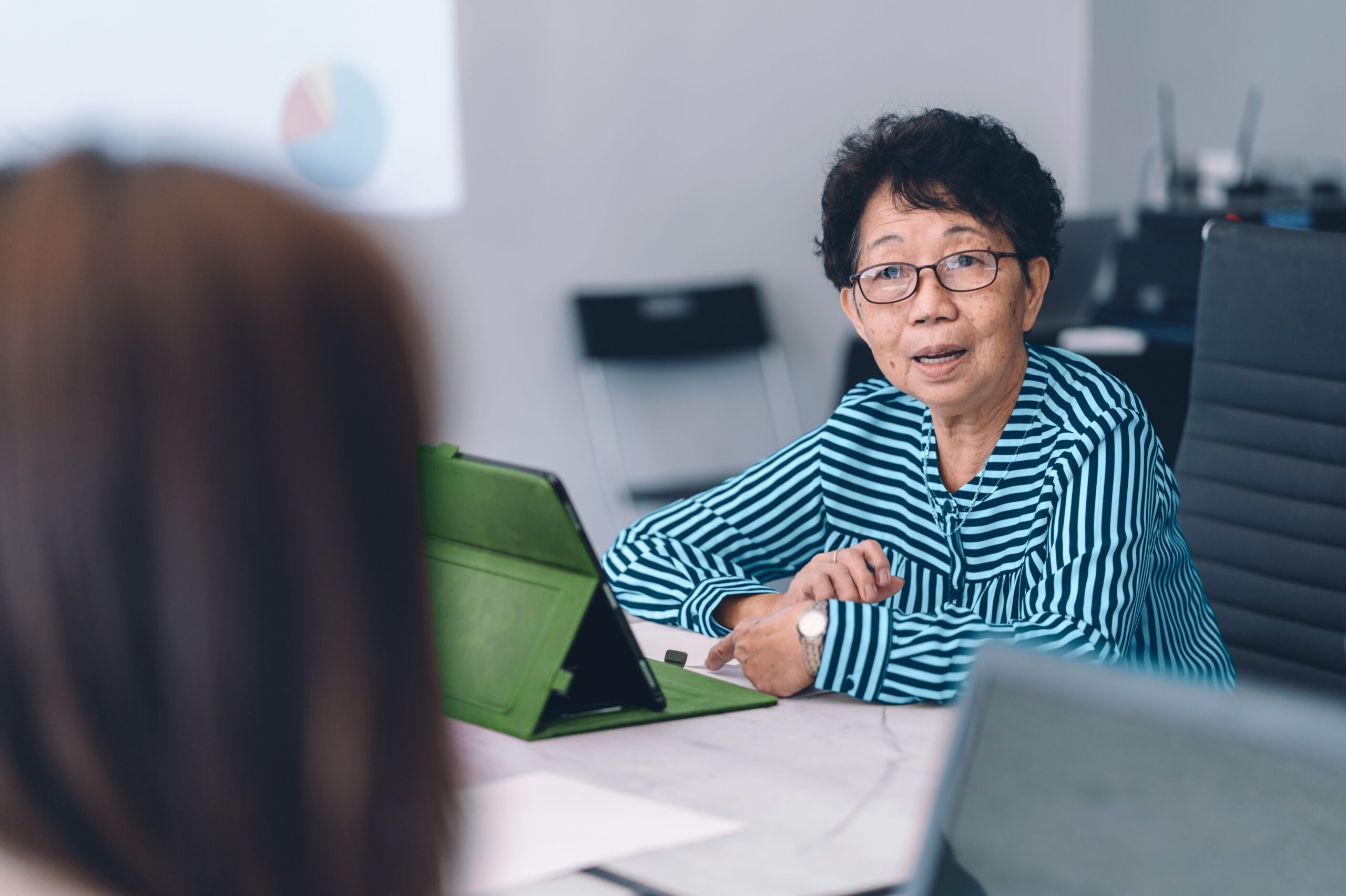 A senior businesswoman runs a meeting using her iPad.