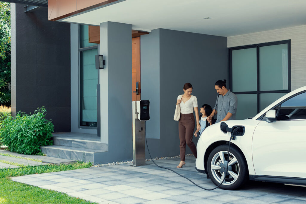 A family stand outside a building with their electric car.