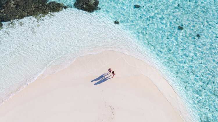 drone view of adult couple on a beach, maldives
