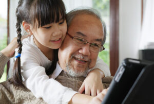 Grandfather and granddaughter use an iPad together.