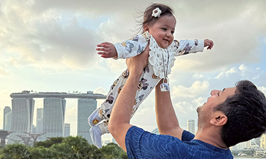 Harshil holds his baby daughter in the air.