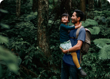 A man an child explore a forest together.