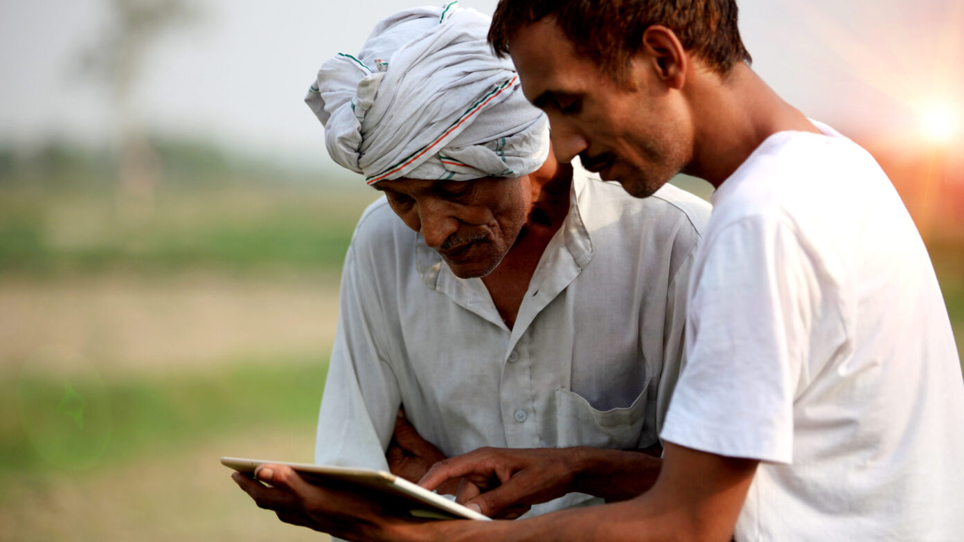 Farmers check their crops and review an Ipad